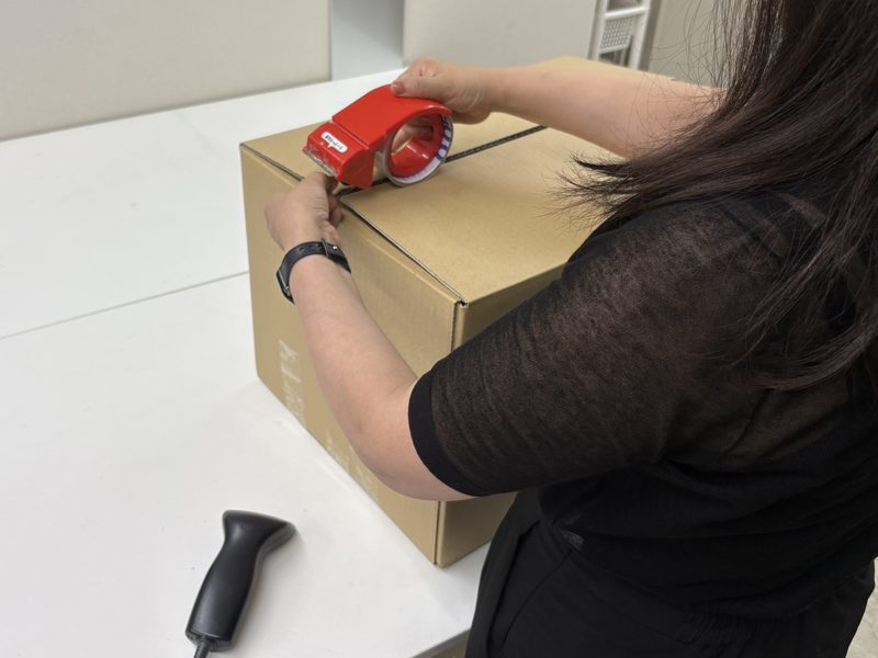 出荷前の段ボールをテープで閉じている手元